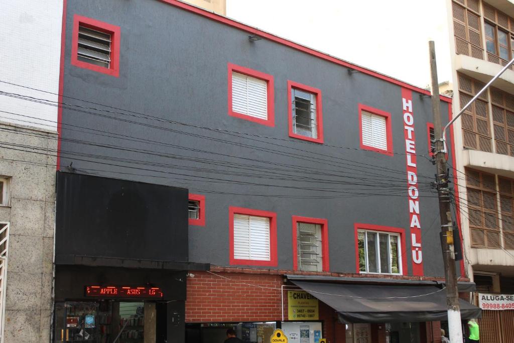 un edificio negro con ventanas rojas en una calle en Hotel Dona Lú en São Paulo