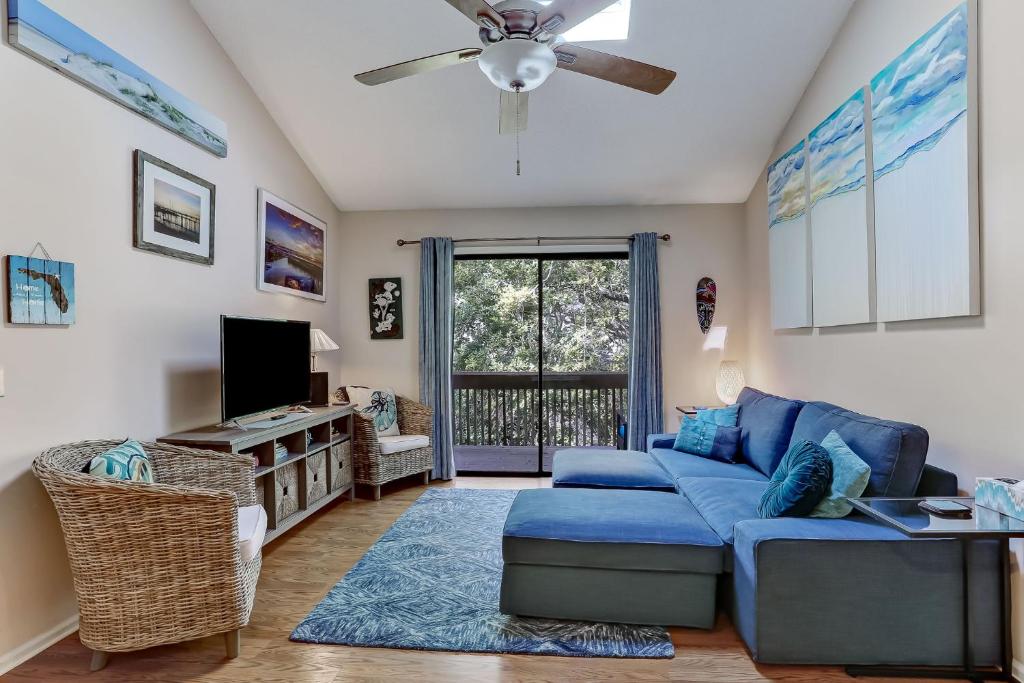 a living room with a blue couch and a ceiling fan at Walk to Beach-Forest Ridge 2747-Pool,Tennis,Pickleball,Playground-Nestled Amongst the Oaks in Fernandina Beach