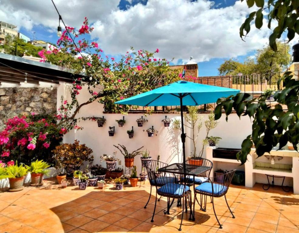 a patio with a table and chairs and a blue umbrella at Villa Sueño Azul B&B in Guanajuato