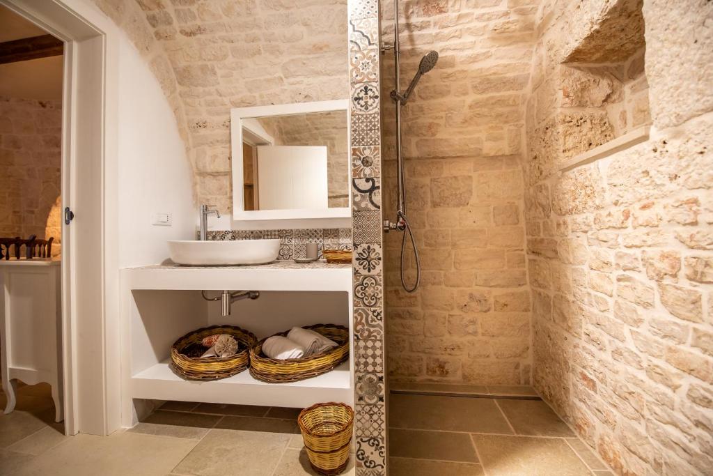 une salle de bain avec douche et lavabo dans l'établissement Il trullo del Guelfo, à Alberobello