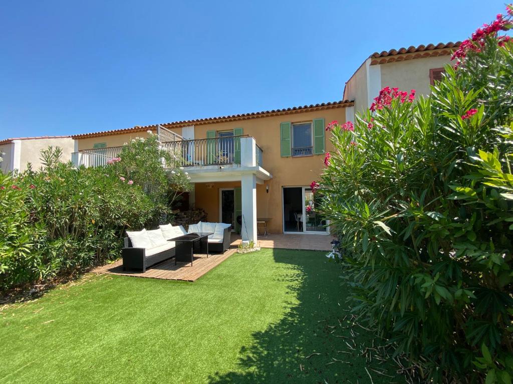 un patio trasero de una casa con césped y flores en Maison avec piscine, climatisée, proche plage, en Roquebrune-sur-Argens