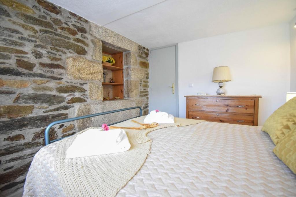 Cama en habitación con pared de piedra en Casinha da Deolinda, en Aldeia das Dez