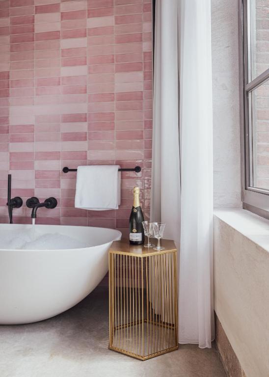 een badkamer met een bad en een fles champagne bij Cousins Boutique Hotel in Maastricht