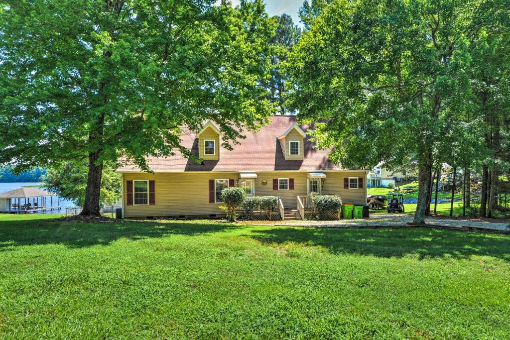 ein gelbes Haus mit Bäumen im Hof in der Unterkunft Beautiful Lakefront Retreat with Dock and Grill! in Littleton