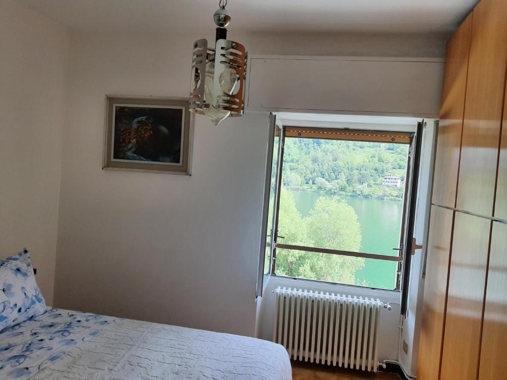 een slaapkamer met een raam met uitzicht op een meer bij CasaEndine in Ranzanico