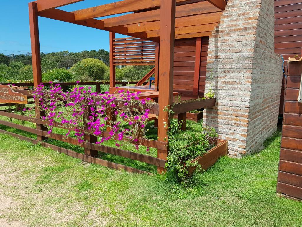 a fence with flowers on it next to a building at Posada Las Maravillas in Punta Del Diablo