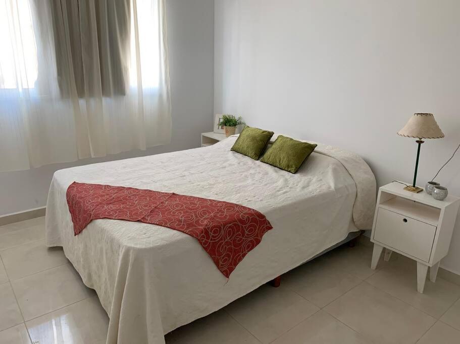 a white bedroom with a large bed with green pillows at Alba II - Departamento 2 ambientes in Posadas