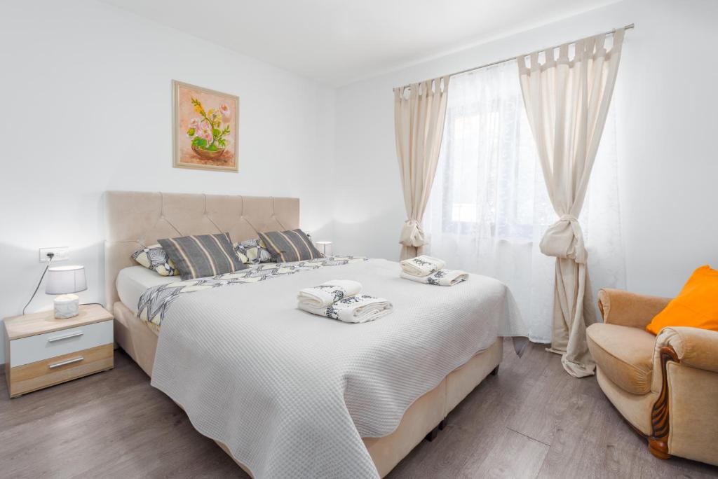 een slaapkamer met een bed, een stoel en een raam bij Alex Deluxe Apartments on Beach in Poreč