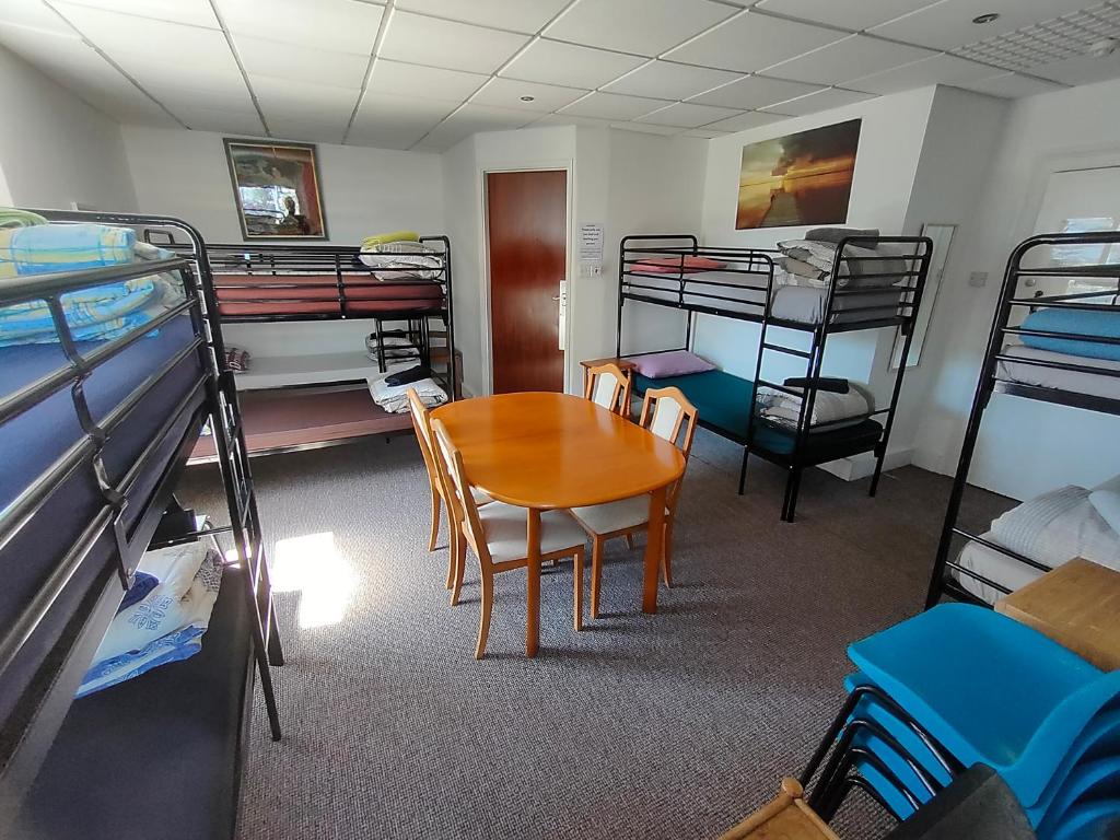 プリマスにあるPlymouth Backpackersの二段ベッド、テーブル、椅子が備わる客室です。