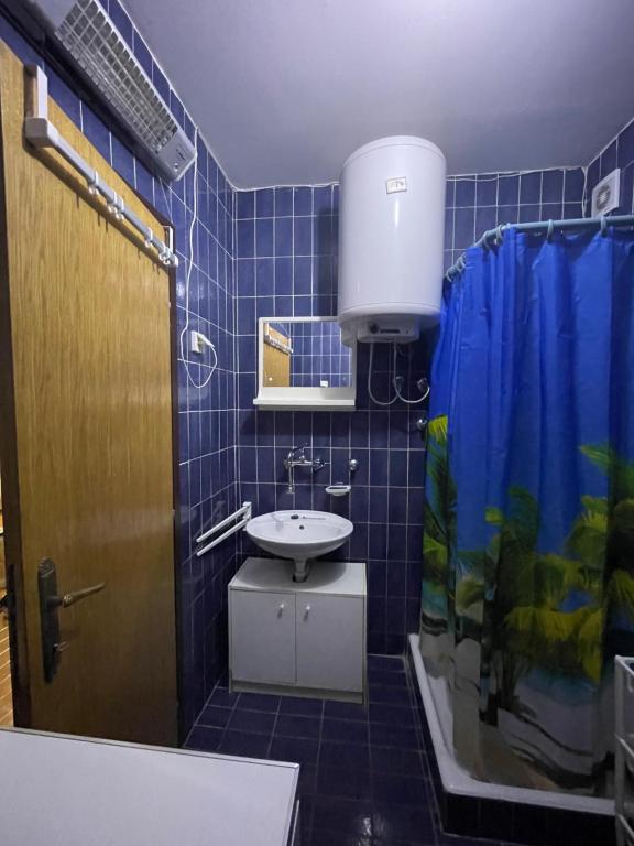 W wyłożonej niebieskimi kafelkami łazience znajduje się toaleta i umywalka. w obiekcie Apartman Lucy w mieście Baošići