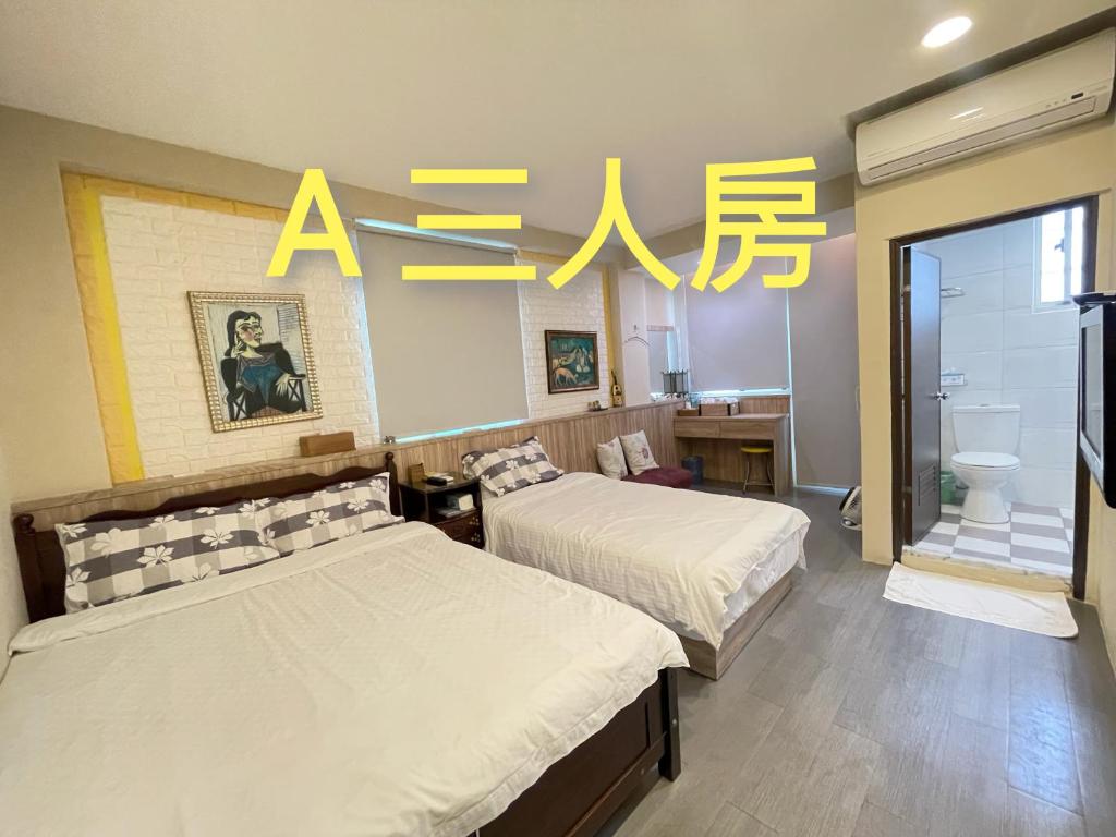 two beds in a room with yellow writing on the wall at Yi Jing BnB in Hualien City