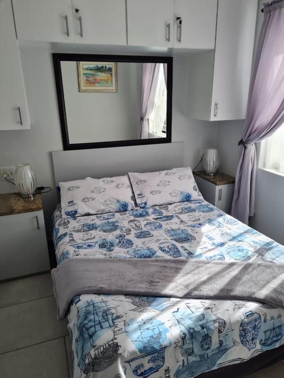 a bedroom with a bed with a blue and white comforter at Flamingo Park Langebaan, 2 Bedroom Apartment in Langebaan