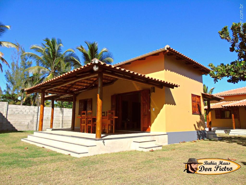 ein kleines gelbes Haus mit einem Tisch und Stühlen in der Unterkunft Bahia Haus Don Pietro in Canavieiras