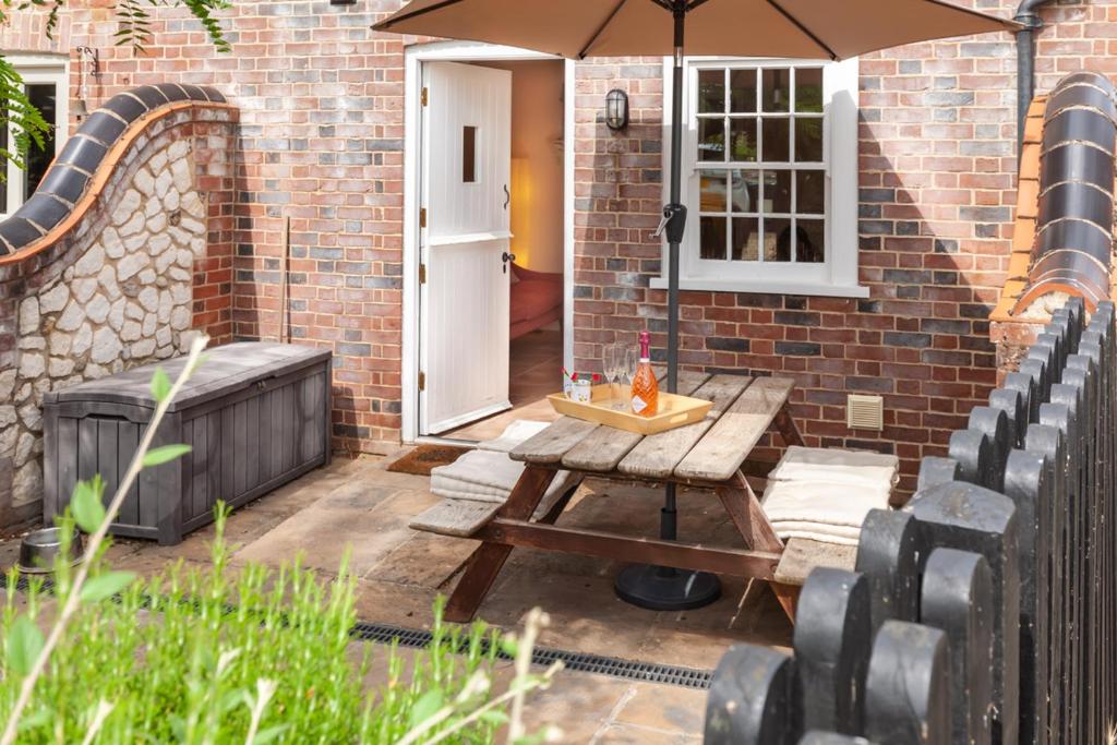a wooden table with an umbrella on a patio at No. 4 Back Lane - Norfolk Cottage Agency in Burnham Market