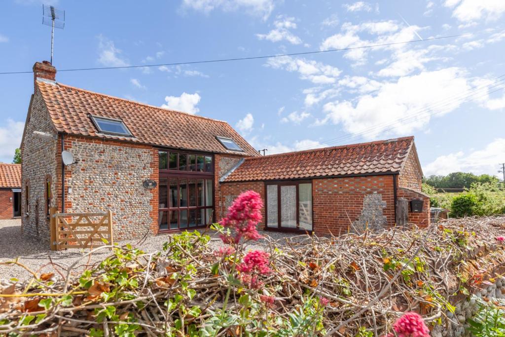 a brick house with flowers in front of it at Meadow Barn - Norfolk Cottage Agency in North Walsham