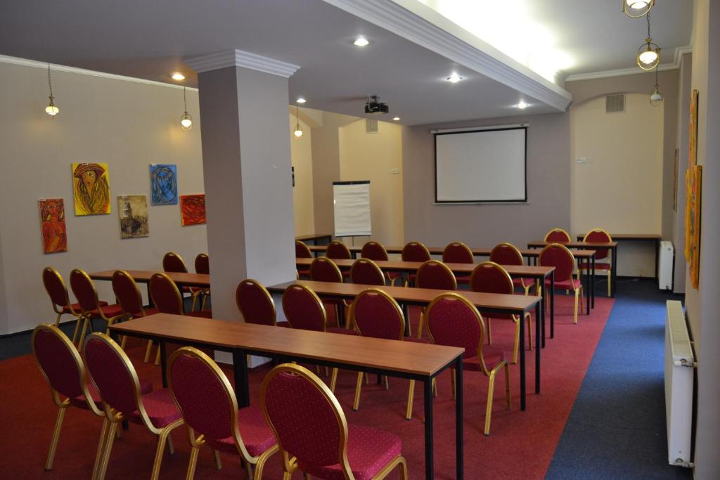 a conference room with tables and chairs and a screen at Hotel Černý Orel Žatec in Žatec