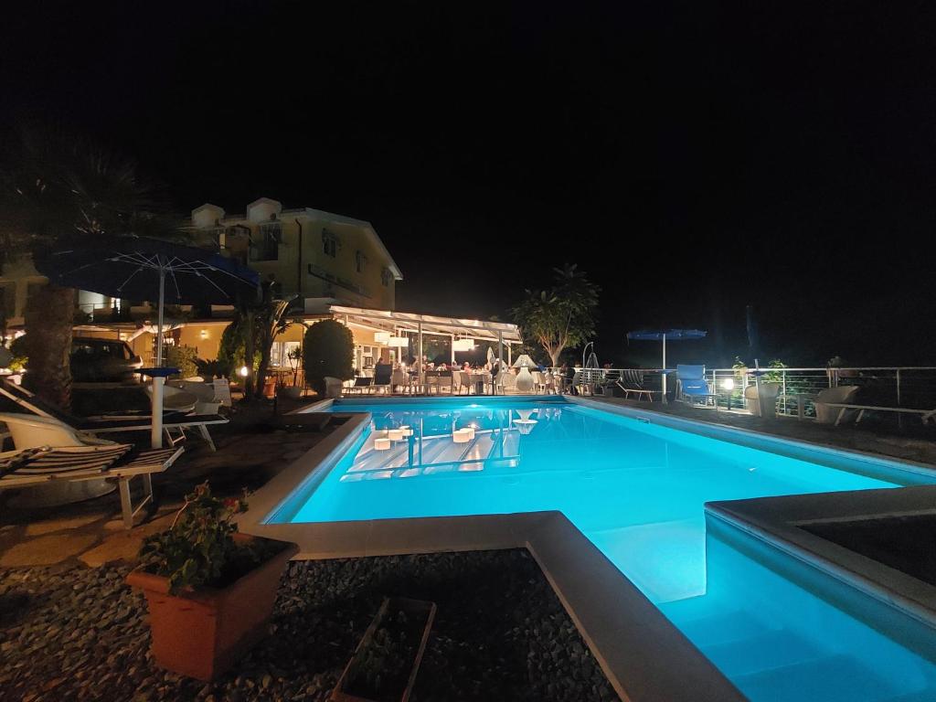 a swimming pool at night with chairs and umbrellas at Hotel Piccolo Mondo in Acquappesa