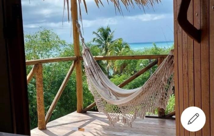 a hammock on a porch with a view of the ocean at Pousada Vila do Alto in Japaratinga