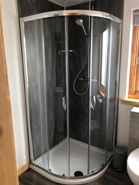 una doccia con porta in vetro in bagno di Lachie's Cabin a Portree