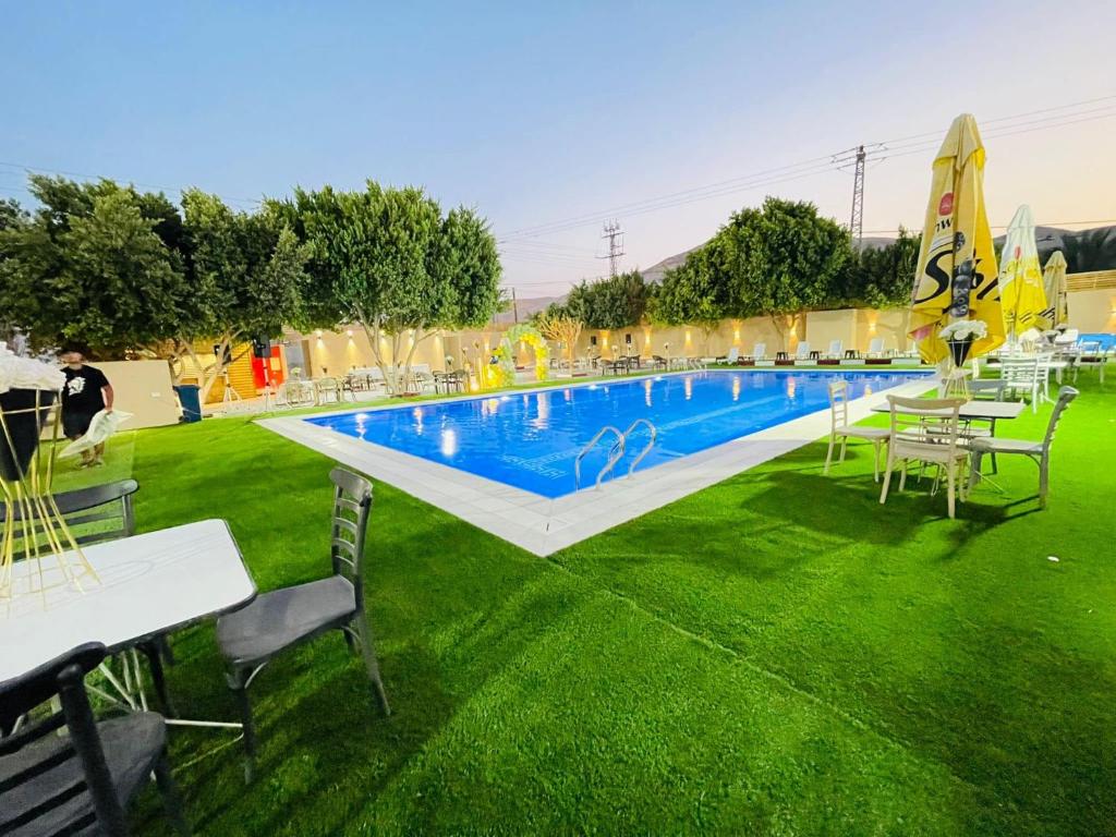 uma piscina com mesas e cadeiras na relva em فندق وادي القلط em Jericó