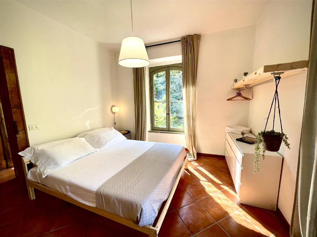 1 dormitorio con cama blanca y ventana en [AvocadoHouse] Incredibile Appartamento Con Vista en San Pellegrino Terme