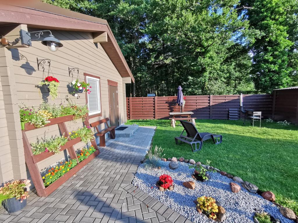 een achtertuin met een patio met een bank en bloemen bij Poilsio namelis Nemirseta in Palanga