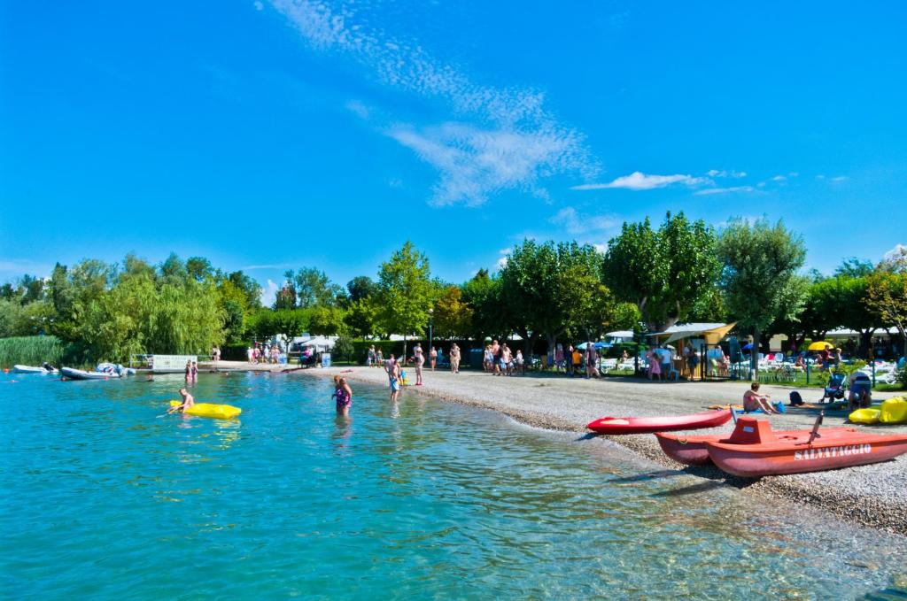 um grupo de pessoas na água em uma praia em Camping Village Du Parc em Lazise