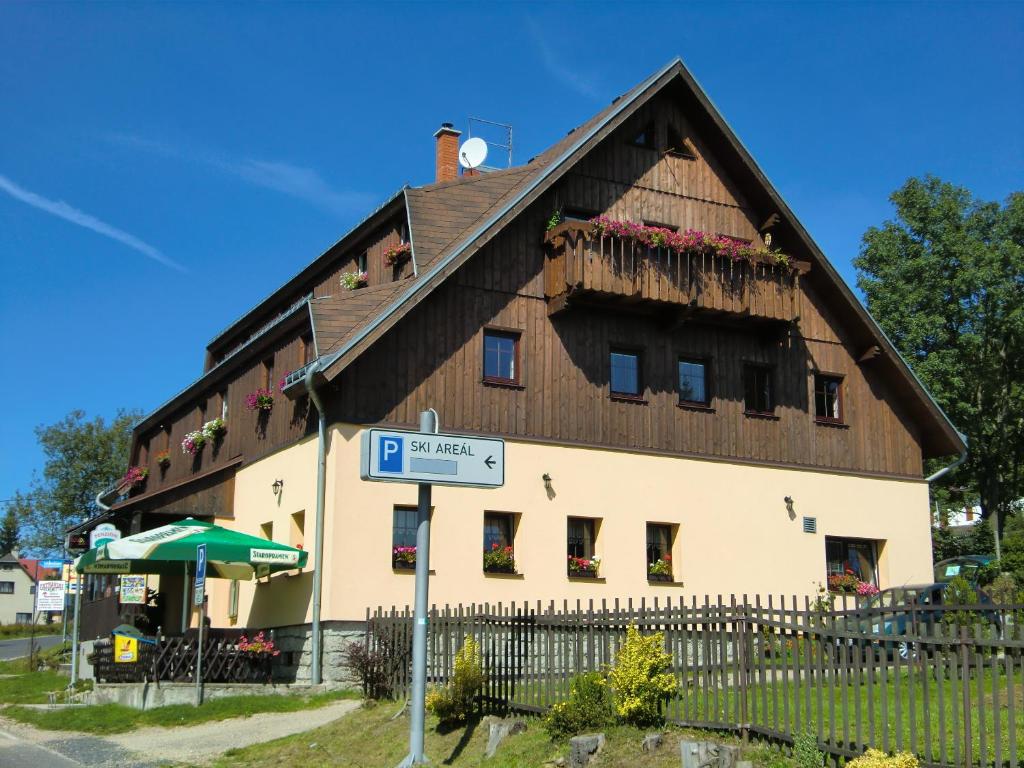 a large wooden building with a sign in front of it at Pension Hela in Bedřichov