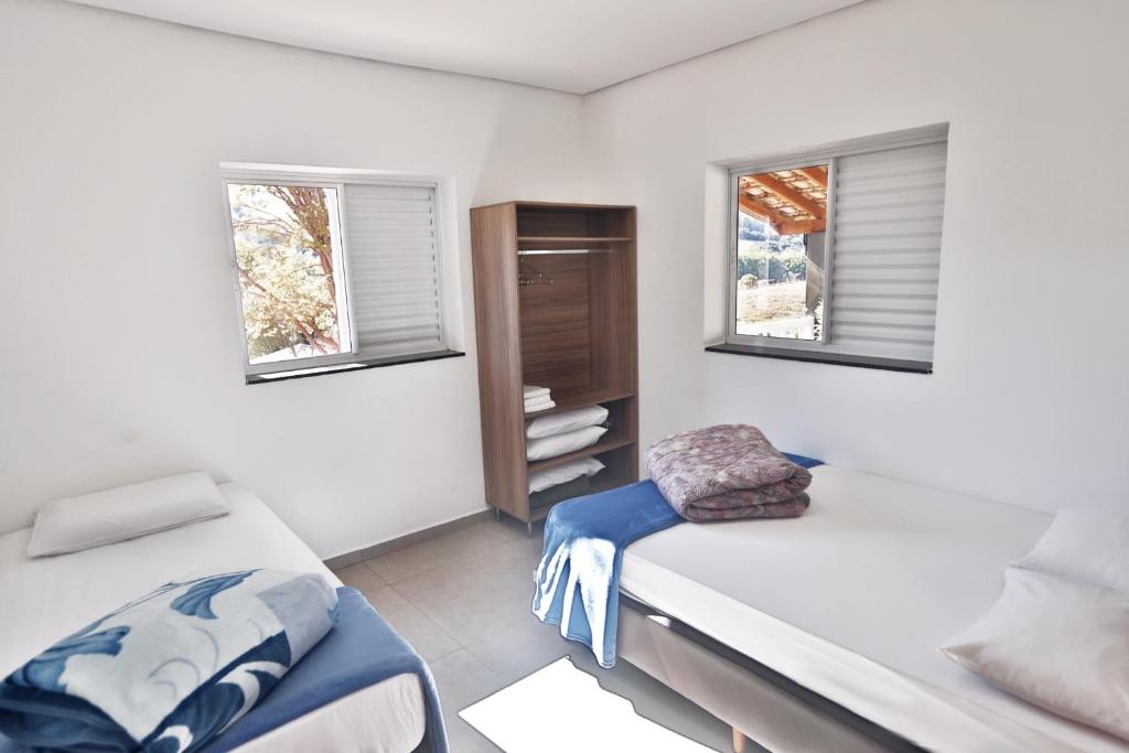 a bedroom with two beds and two windows at Complexo de Lazer Paraíso Rural in São Thomé das Letras