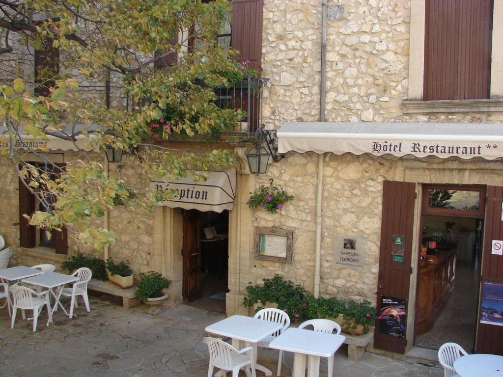 un bâtiment avec des tables et des chaises à l'extérieur dans l'établissement Logis Hôtel Restaurant Les Géraniums, à Le Barroux