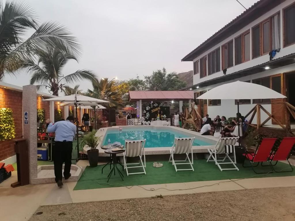 a man walking by a pool with chairs and a table at Hospedaje PILARES DE BOCAPAN in Bocapán