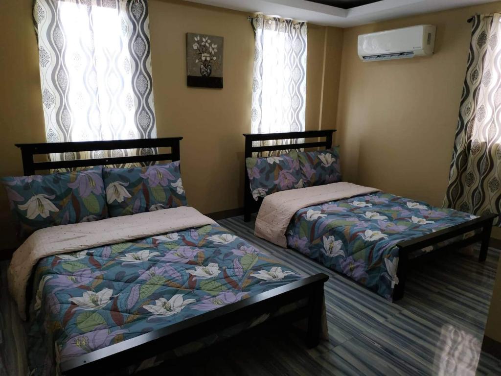 two beds sitting in a room with windows at Blk 40 lot 35 Pueblo de oro la aldea del monte sto tomas batangas in San Rafael