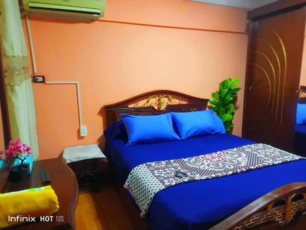 1 dormitorio con 1 cama con sábanas azules y paredes de color naranja en Fayrouzat Smoha near the city with open view, en Alejandría