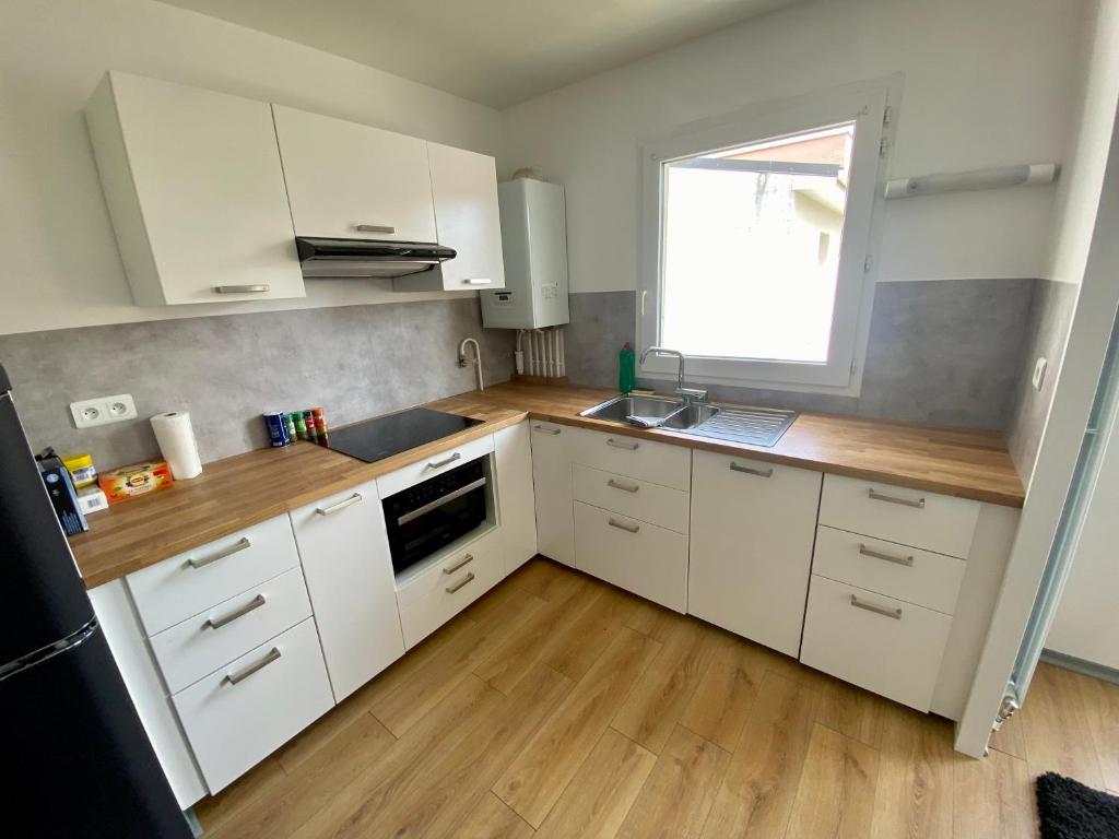 a kitchen with white cabinets and a sink and a window at Le cœur de Rive gauche - Superbe T3 - parking - 082 in Rouen