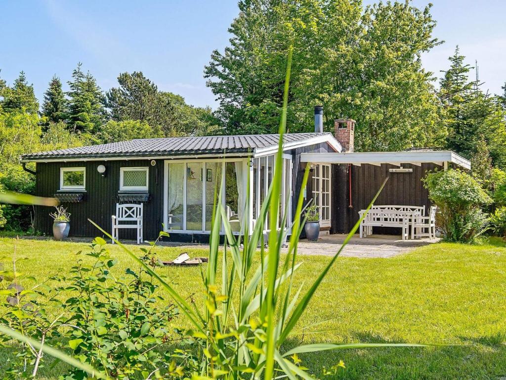 ein kleines grünes Cottage mit einer Bank im Hof in der Unterkunft Holiday home Væggerløse CCXIV in Bøtø By