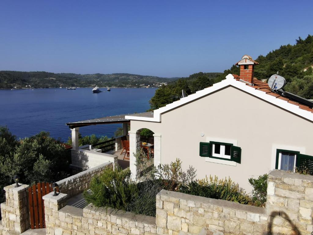 une maison blanche avec vue sur l'eau dans l'établissement Secluded fisherman's cottage Cove Picena, Korcula - 14090, à Vela Luka