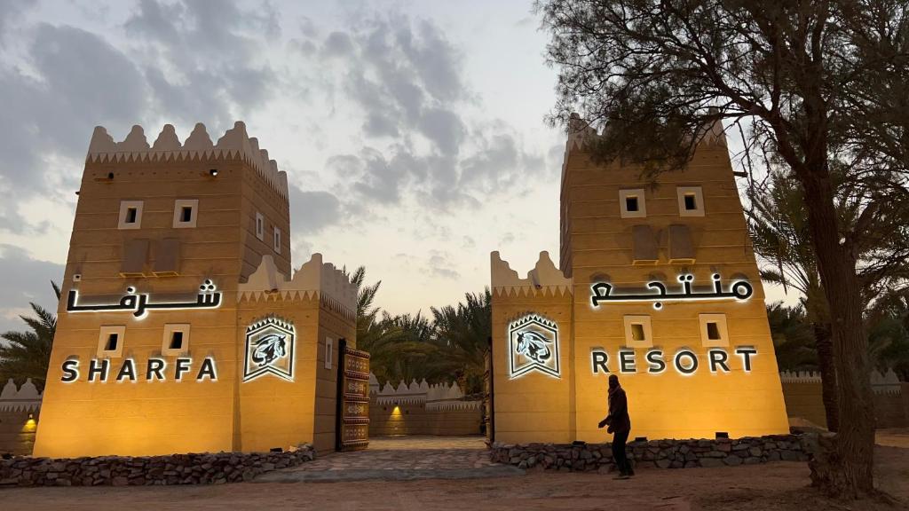 un hombre está parado frente a un castillo en منتجع شرفا السياحي البيئي, en Hail