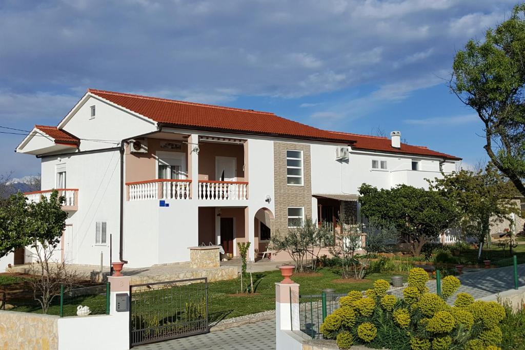 une maison blanche avec un toit rouge dans l'établissement Apartments with a parking space Vrsi, Zadar - 14211, à Vrsi