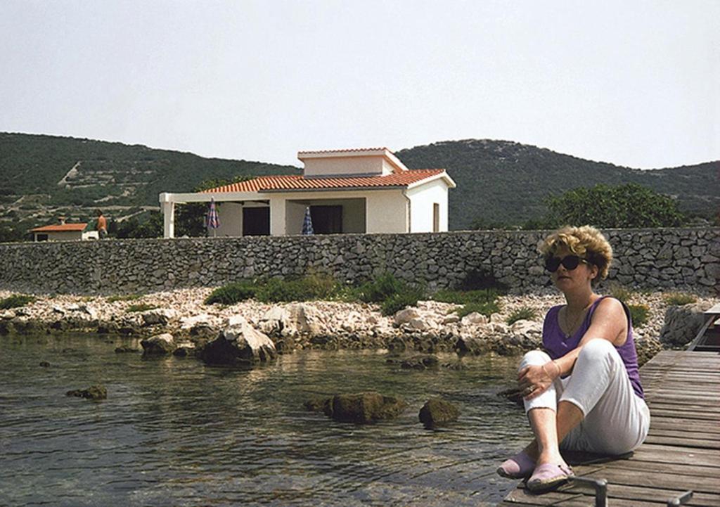 Eine Frau, die auf einem Steg im Wasser sitzt. in der Unterkunft Seaside holiday house Ist - 14366 in Ist