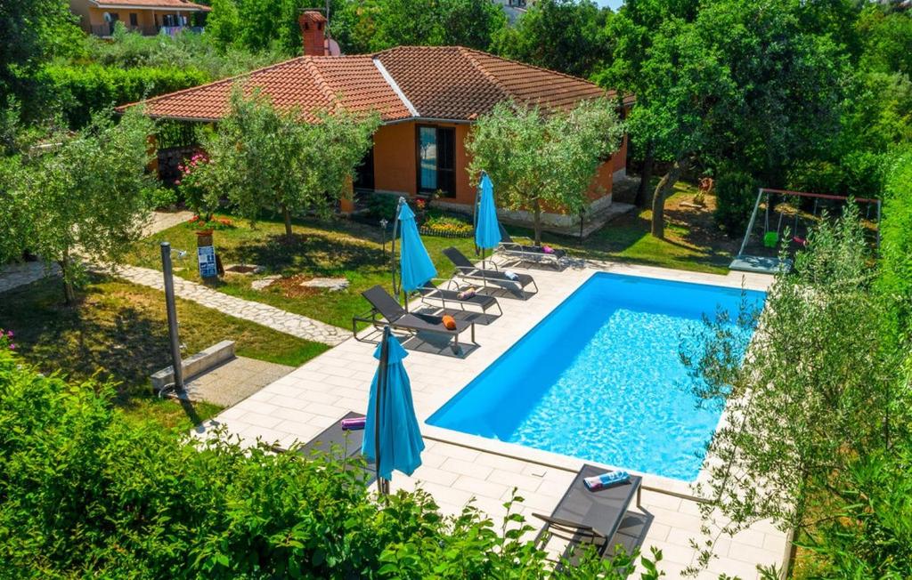 - une piscine avec des chaises et des parasols à côté d'une maison dans l'établissement Family friendly house with a swimming pool Sveti Lovrec, Central Istria - Sredisnja Istra - 14432, à Sveti Lovreč Pazenatički