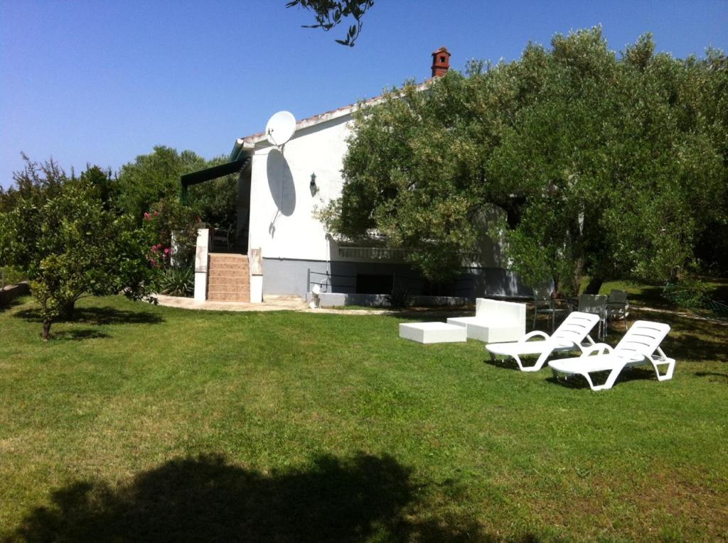 een groep witte stoelen in het gras voor een gebouw bij Holiday house with a parking space Kozino, Zadar - 14464 in Petrcane