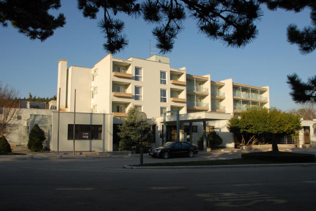 Un bâtiment blanc avec une voiture garée devant. dans l'établissement Rooms with a parking space Sinj, Zagora - 14466, à Sinj