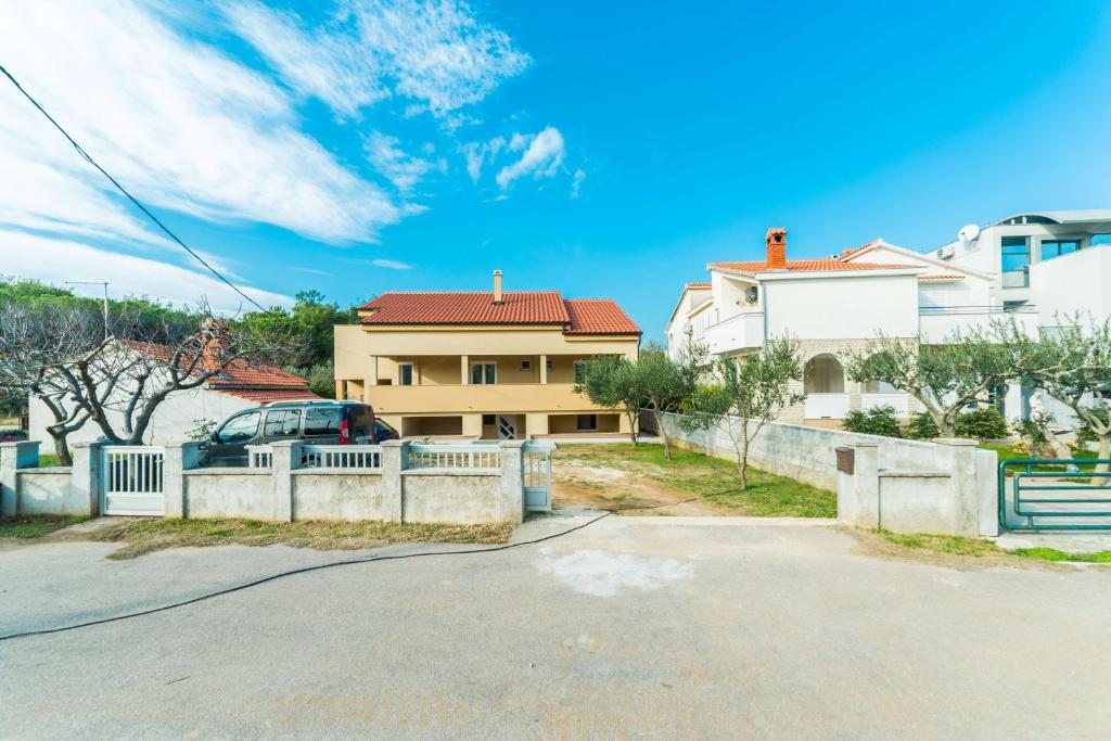 uma casa com uma cerca em frente a uma rua em Apartments with a parking space Privlaka, Zadar - 14492 em Privlaka