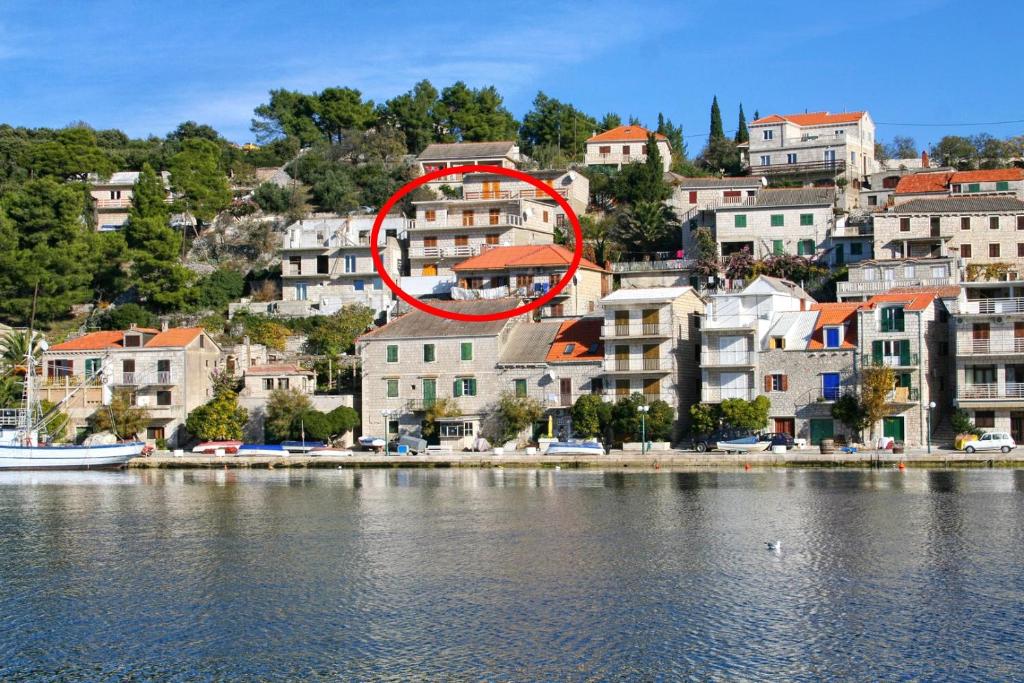 einem roten Kreis auf einem Gebäude neben einem Wasserkörper in der Unterkunft Apartment Povlja 14399c in Povlja