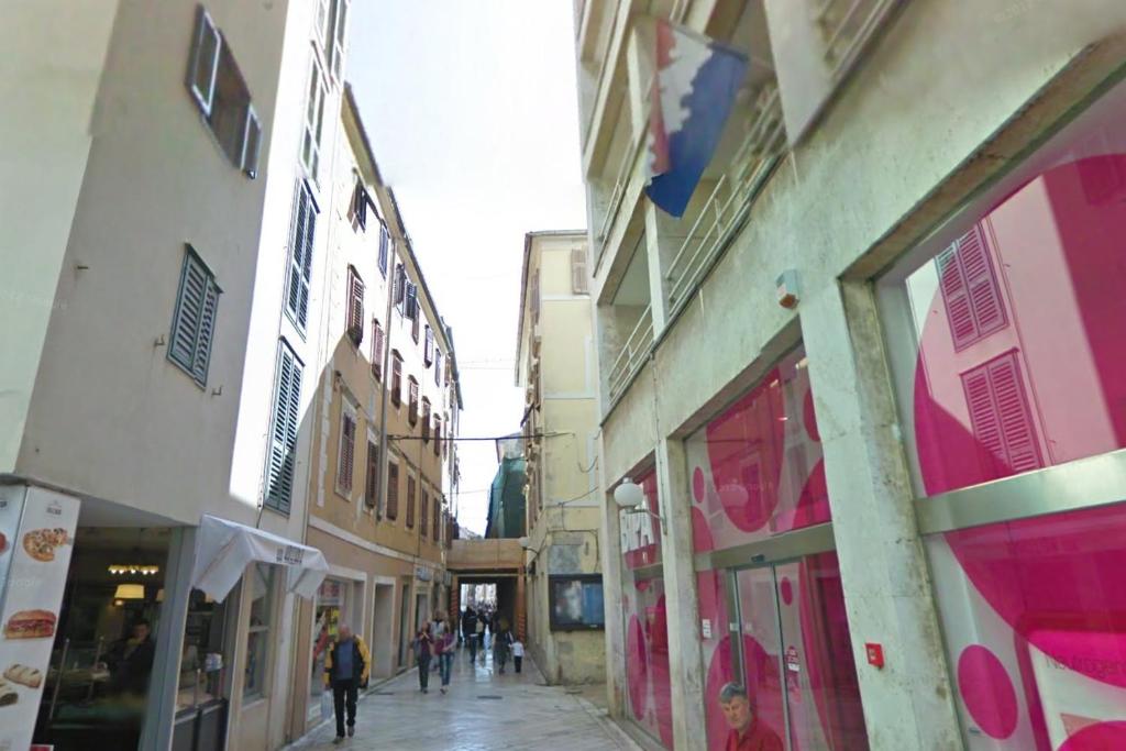 Un groupe de personnes marchant dans une rue avec des bâtiments dans l'établissement Apartments with WiFi Zadar - 14525, à Zadar