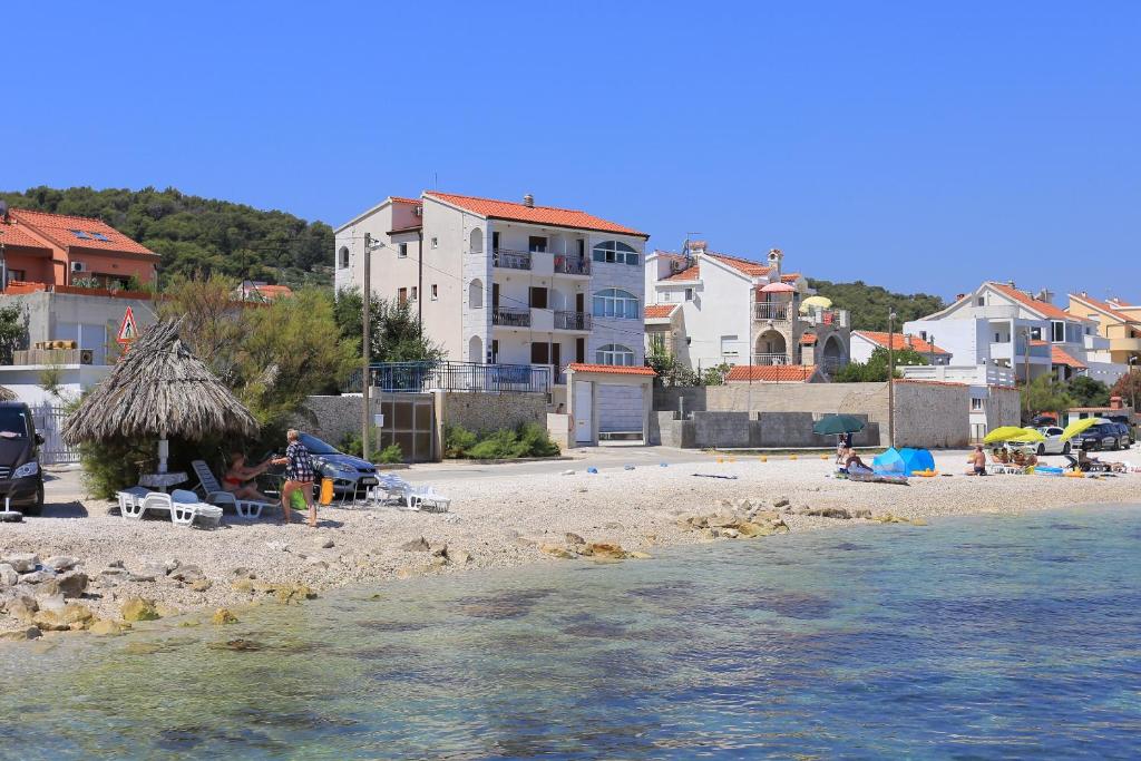a group of people sitting on a beach near the water at Apartments by the sea Slatine, Ciovo - 14541 in Slatine