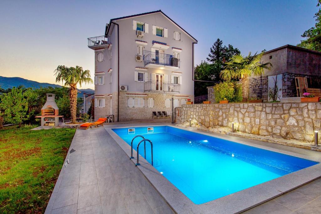 een huis met een zwembad voor een gebouw bij Family friendly apartments with a swimming pool Rijeka - 14294 in Rijeka