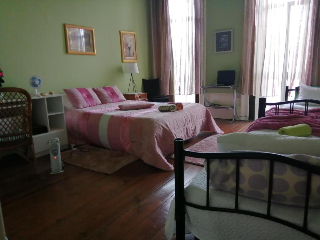 a bedroom with two beds with pink sheets at Casa dragão in Porto