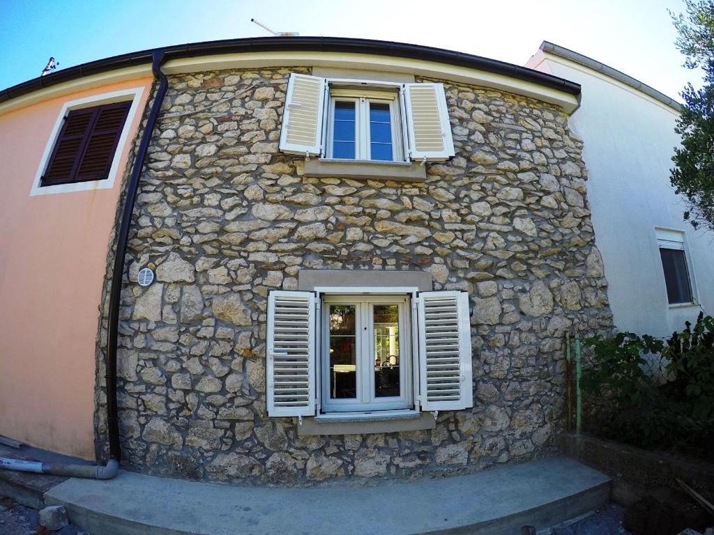 un edificio de piedra con ventana y persianas blancas en Holiday house with a parking space Nin, Zadar - 14295, en Nin