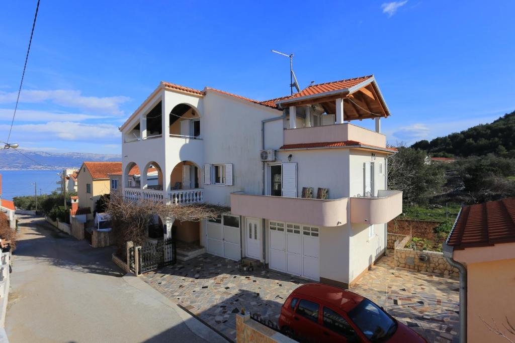 a white house with a car parked in front of it at Apartments by the sea Slatine, Ciovo - 16341 in Slatine